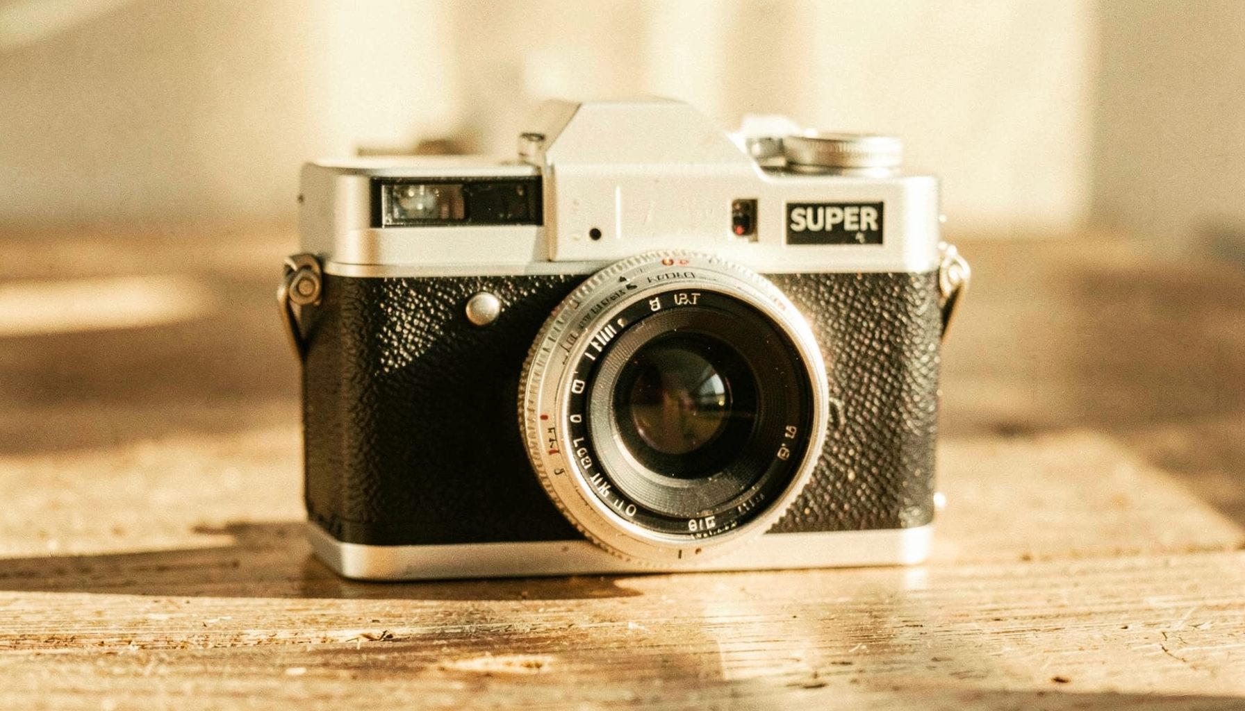 Vintage Super 8 film camera on a wooden surface, warm sunlight casting soft shadows, cream and beige tones